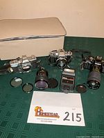 Lot overview showing three Minolta cameras, two lenses, flash, filters, caps and beige case