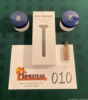 Front view showing sealed Solawave box, two Shalimar jars with blue lids, vintage perfume bottle
