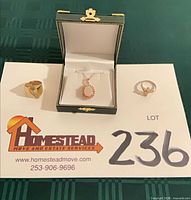 Full lot view showing necklace in box and two rings