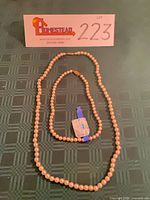 Both cream pearl necklaces laid flat showing full lengths and tag
