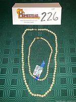 Two cream pearl necklaces displayed flat, longer and shorter strands visible