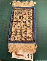 Full view of rug on green background showing entire design and fringe