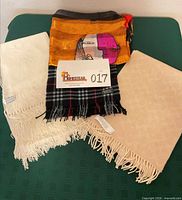 All four scarves and shawls laid out together displaying colors and fringe