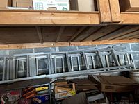 Two aluminum ladders stored horizontally on wall supports