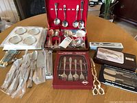 Overall view of boxed flatware sets, cheese set, shears, coasters, and loose serving pieces