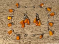Necklace laid flat showing amber drops and two accessory pieces