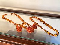 Both amber necklaces displayed on glass top surface