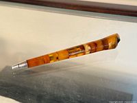 Full side view showing amber segmented pen and metal tip