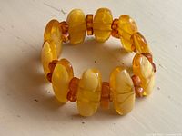 Full view of stretch bracelet showing large oval amber beads and smaller spacers