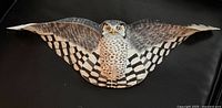 Full frontal view of carved hawk owl sculpture showing entire wingspan and body