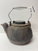 Side view of cast iron kettle showing spring handle and rust
