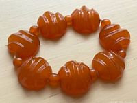 Top view showing carved side of six large amber-tone beads and spacers