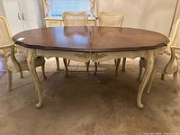 Full view of oval dining table with walnut top and painted base