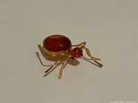 Oblique view of amber spider brooch showcasing body, head, legs and pin setting