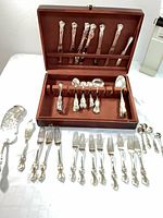 Overall view of flatware laid out with wood chest