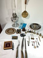Full layout showing lamp, spatula, plates, bells, ashtrays, abacus, carving set, mother-of-pearl pieces, souvenir spoons, bottle opener, Huacas display