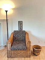 Front view of rattan armchair, basket and floor lamp