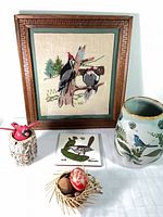 Group shot showing embroidered picture, ceramic vase, roadrunner tile, wood bird decor, and wicker nest with eggs
