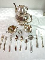 Full lot showing coffee pot, creamer, sugar bowl, napkin ring and assorted flatware