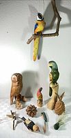 Group view of all wooden bird figures, fruit forms and branch-mounted parrot