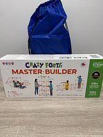 Front of Crazy Forts Master Builder box beside blue drawstring bag