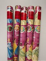 Five sealed rolls standing upright showing labels and princess graphics
