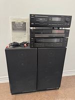 Full lot view showing three JVC components stacked on two black speakers