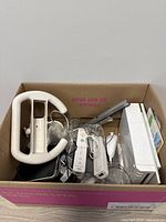 Box with Wii console, two remotes, nunchuk, wheel, sensor bar, stand visible