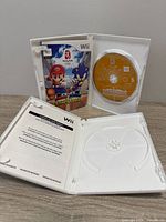 Open Mario & Sonic case showing disc and manual, empty second case visible