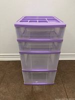 Front view of 4-drawer clear plastic storage unit with purple accents
