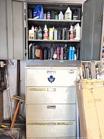 View of two cabinets showing numerous motor-oil bottles and other fluids