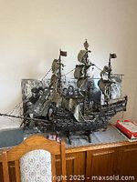 Full view of the model sailing ship showing hull, masts, sails and rigging on tabletop