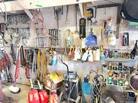 Pegboard wall with wrenches, pipe wrenches, extension cord, spray bottles, paint cans, gas cans, welding unit
