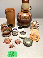 Entire lot arranged showing jug, terracotta vase, small candle holders, coasters, figurines, stone
