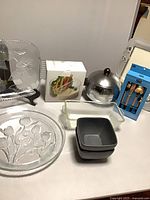 Group shot of all items: glass platter, round plate, boxed accessory, glass baker, stoneware bowls, stainless ice bucket