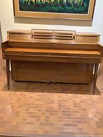 Full front view of medium brown Nordheimer console upright piano with music rest and pedals
