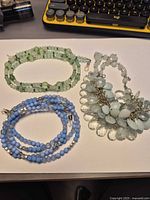 Three necklaces laid flat showing overall design and colors
