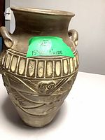 Front view showing urn shape, handle, carved relief and patina