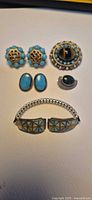 Entire lot laid out: two earring pairs, brooch, pin, watch band
