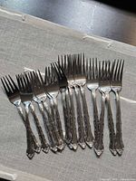 Full set of 16 Imperial Stainless Rose Garland forks fanned out on cloth