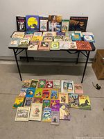 Overall view of lot on table and floor showing quantity and variety of books
