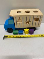 Truck with container and four shapes next to measuring tape showing 11 in length