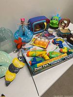 All toys laid out including water blasters in packaging, microwave, doll, jewelry box, toy car, balls and accessories