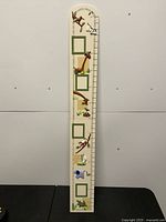 Full front view of cream wooden growth chart with jungle animals and photo frames