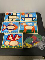 Overview of five wooden puzzle boards and bag of coloured pieces