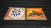 Both CD cases, Britney open showing disc, Monkees closed