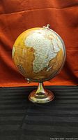 Front view of yellow world globe on metal stand