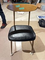 Front view of chair showing wood backrest and black vinyl seat