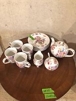 Whole set on table showing plates, mugs, teapot, sugar bowl, creamer