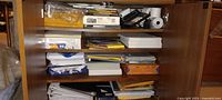 Four shelves filled with paper, envelopes, binders, mailers, calculator rolls